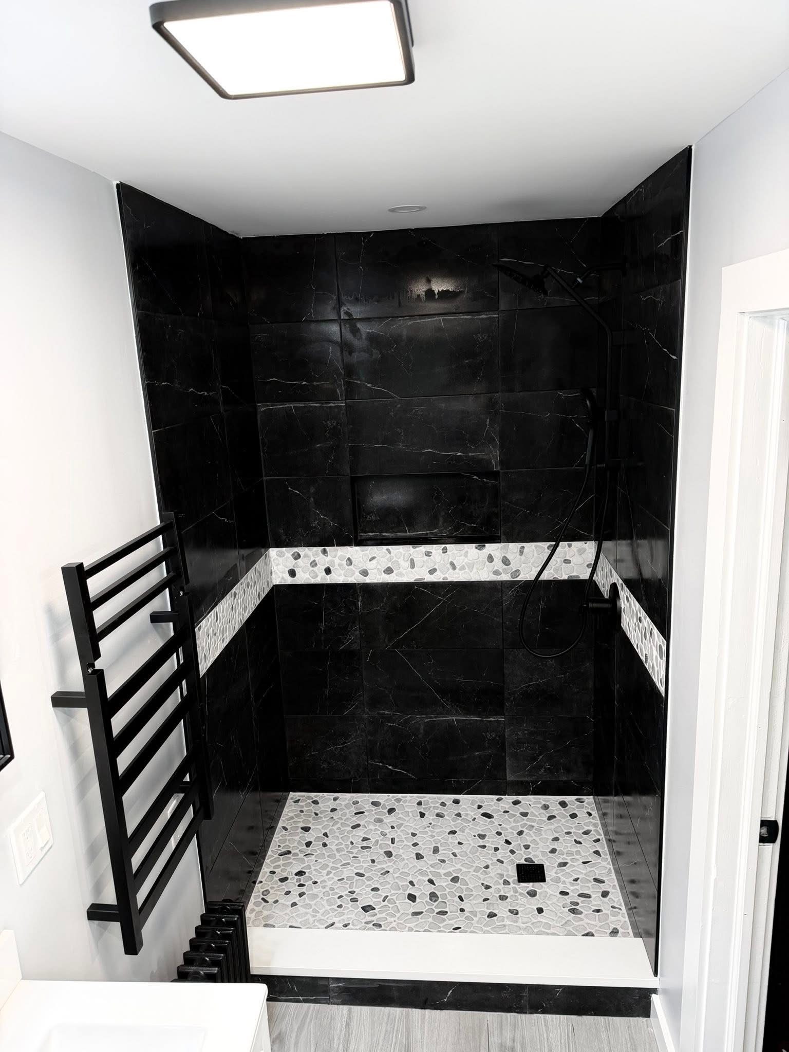 Walk-in shower close up — black marble and pebble mosaic