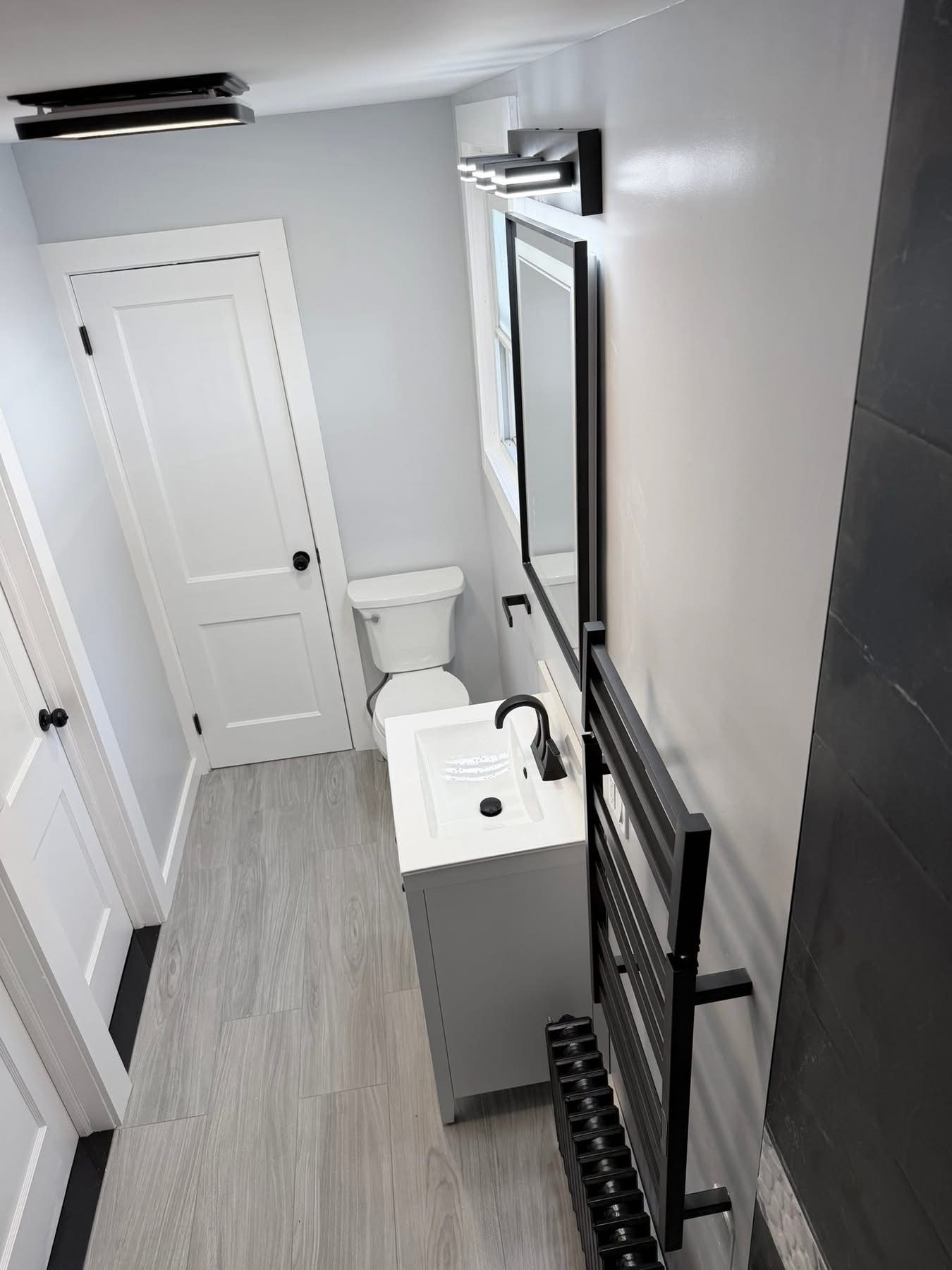 Full bathroom overview — wood floor tile and gray vanity