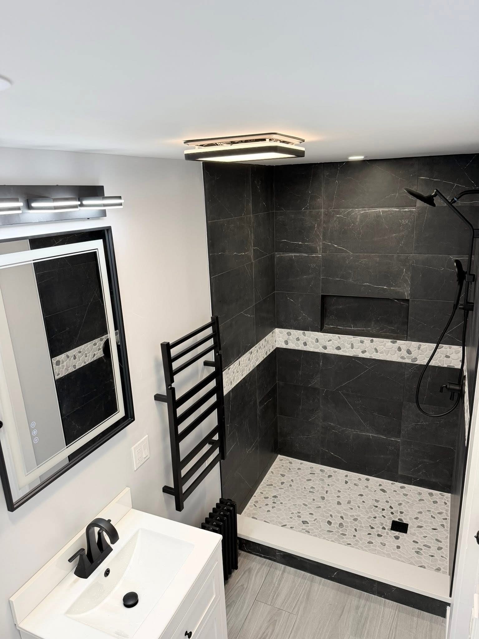 After: luxury walk-in shower renovation — black marble tile, pebble floor, heated towel rack — Westchester NY